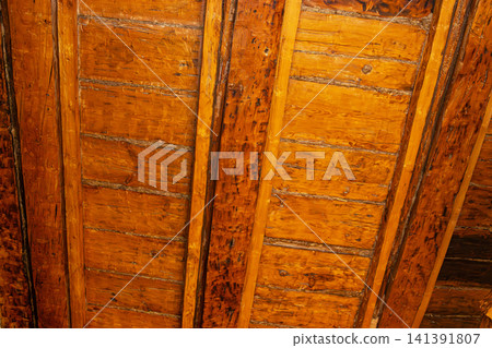 Detailed view of weathered wooden ceiling panels with rich orange and brown tones, showcasing natural wood texture and aged patina 141391807