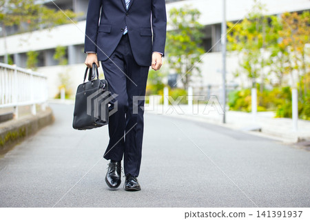 一位二十多歲的商人正在戶外散步。 一位二十多歲的商人正在戶外散步。 141391937