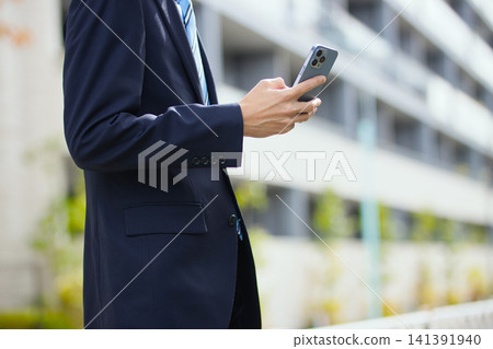 一位二十多歲的商人手持智慧型手機在戶外。 一位二十多歲的商人手持智慧型手機在戶外。 141391940