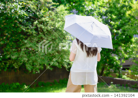 一位二十多歲的女子撐著陽傘。 一位二十多歲的女子撐著陽傘。 141392104