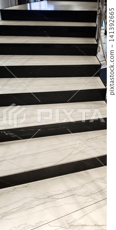 Steps made of black and white marble lead to a second floor in a building Steps made of black and white marble lead to a second floor in a building 141392665