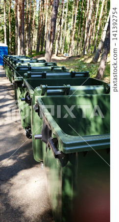 Line of trash cans in a wooded area during daylight hours Line of trash cans in a wooded area during daylight hours 141392754