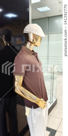 Display of a mannequin wearing brown polo shirt and white pants in a retail store Display of a mannequin wearing brown polo shirt and white pants in a retail store 141392770
