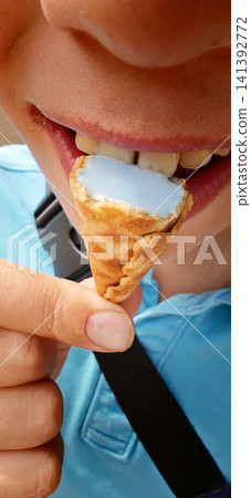 Child enjoys ice cream cone on a sunny day outdoors in the park Child enjoys ice cream cone on a sunny day outdoors in the park 141392772