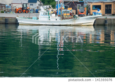 A white fishing boat docked in a quiet fishing port. A white fishing boat docked in a quiet fishing port. 141393076