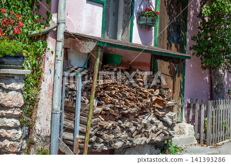 Large Pile of Cut Firewood under a Sheltered Pink Facade in Rustic Alpine village Large Pile of Cut Firewood under a Sheltered Pink Facade in Rustic Alpine village 141393286
