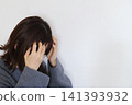 A woman holding her head in her hands in distress - an image of stress 141393932