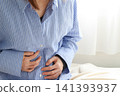 Image of a woman holding her stomach, experiencing abdominal pain or feeling unwell. 141393937