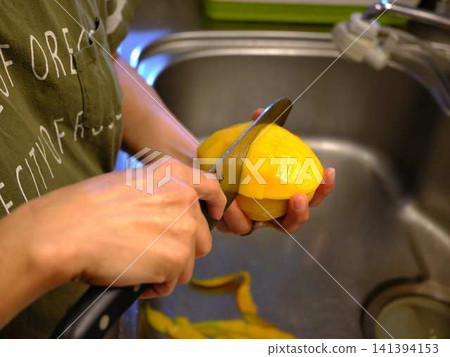 The hands of a woman cutting a mango 141394153