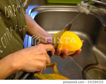 The hands of a woman cutting a mango 141394155