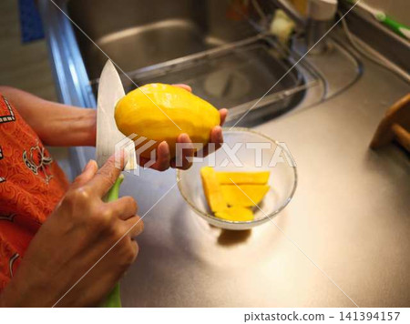 The hands of a woman cutting a mango The hands of a woman cutting a mango 141394157