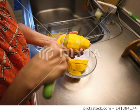 The hands of a woman cutting a mango 141394174
