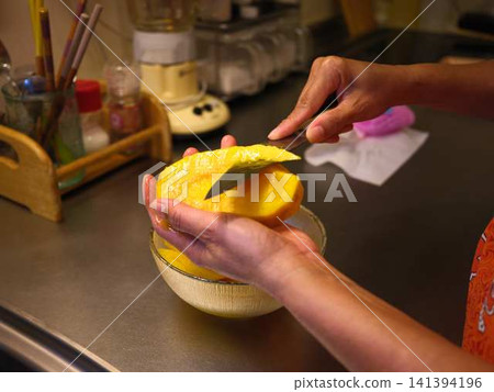 The hands of a woman cutting a mango The hands of a woman cutting a mango 141394196