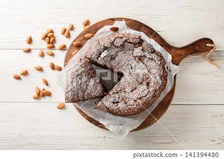 Torta caprese is a flourless chocolate cake made with almonds closeup on the wooden board. Horizontal top view 141394480