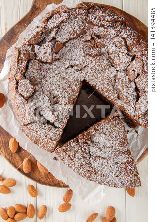 Italian torta caprese: this chocolate and almond cake is dense, rich and moist closeup on the wooden board on the table. Vertical top view 141394485