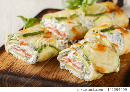 Close-up of sliced zucchini roll stuffed with salmon and cream cheese on a wooden board. Horizontal Close-up of sliced zucchini roll stuffed with salmon and cream cheese on a wooden board. Horizontal 141394499