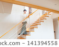 A young woman descending a staircase with a handrail. 141394558