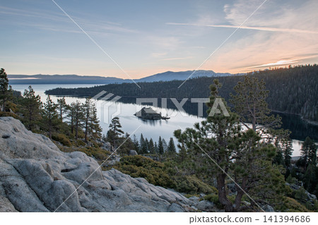 Beautiful serene lake surrounded by mountain rock and tall pine tree with small island during sunset landscape in sierra nevada usa bringing deeply peaceful feeling Beautiful serene lake surrounded by mountain rock and tall pine tree with small island during sunset landscape in sierra nevada usa bringing deeply peaceful feeling 141394686
