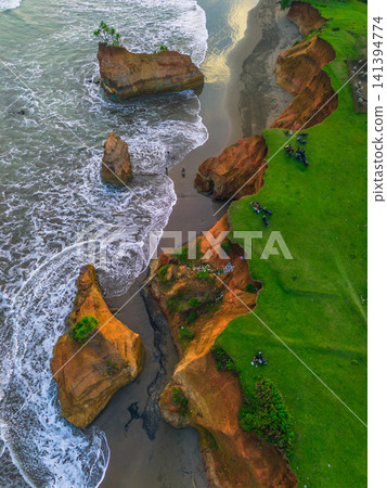 Aerial view of coastal rock formations rising from the sea with crashing waves and sandy beach in Indonesia Aerial view of coastal rock formations rising from the sea with crashing waves and sandy beach in Indonesia 141394774