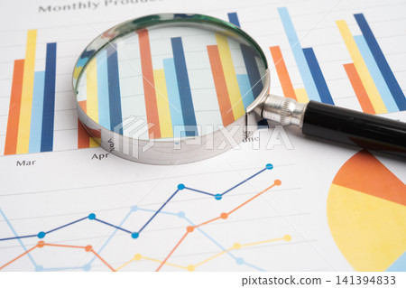 Magnifying glass on charts graphs paper. Magnifying glass on charts graphs paper. 141394833