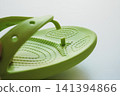 Green flip-flops with the strap detached and damaged. 141394866
