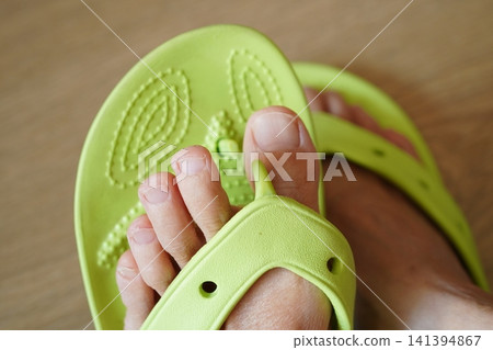 Close-up of a plastic sandal with a broken thong. Close-up of a plastic sandal with a broken thong. 141394867