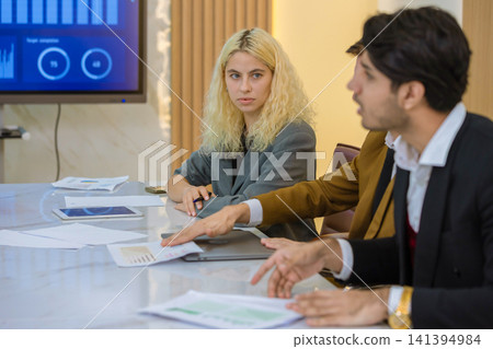Diverse colleagues gather in brainstorm discuss statistics together. Diverse colleagues gather in brainstorm discuss statistics together. 141394984