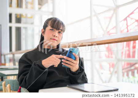 Thai Transgender Woman Using Blue Smartphone Near Window 141395172