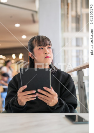 Thai Transgender Woman Holding Digital Tablet and Looking Away Thai Transgender Woman Holding Digital Tablet and Looking Away 141395176