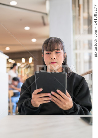 Thai Transgender Woman Looking at Tablet Screen in Bright Cafe Thai Transgender Woman Looking at Tablet Screen in Bright Cafe 141395177