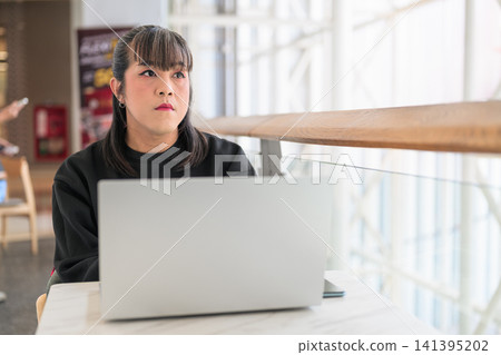Thai Transgender Woman Working on Laptop and Looking Out Window Thai Transgender Woman Working on Laptop and Looking Out Window 141395202
