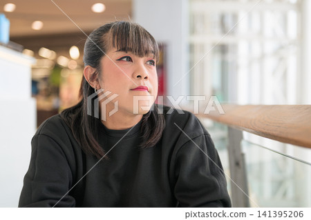 Thai Transgender Woman Looking Sideways Indoors Beside Glass Railing Thai Transgender Woman Looking Sideways Indoors Beside Glass Railing 141395206