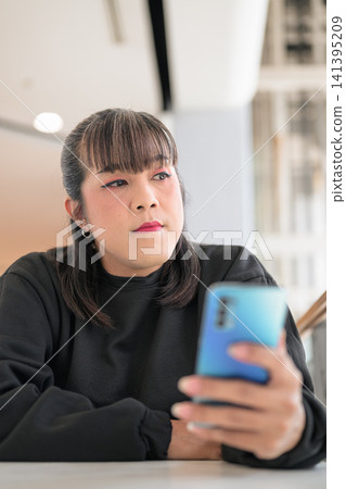 Close-Up of Thai Transgender Woman Holding Phone and Gazing Away Close-Up of Thai Transgender Woman Holding Phone and Gazing Away 141395209