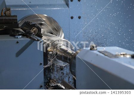 A close-up shot of coolant splashing as a metal shaft is machined on a CNC lathe. A close-up shot of coolant splashing as a metal shaft is machined on a CNC lathe. 141395303