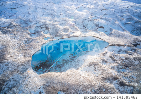 Aerial view of Perito Moreno glacier showing climate change impacts with melting blue pool. Melancholy scene displays nature power and environmental loss through dramatic ice surface textures Aerial view of Perito Moreno glacier showing climate change impacts with melting blue pool. Melancholy scene displays nature power and environmental loss through dramatic ice surface textures 141395462