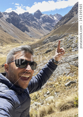 Man pointing at mountain peak in rugged valley. UGC Man pointing at mountain peak in rugged valley. UGC 141395485