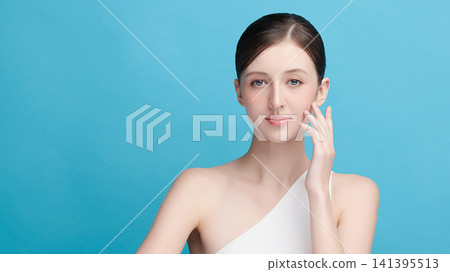 A beautiful young Asian woman with clean, fresh skin against a blue background. Skincare, facial treatment, cosmetology, beauty, and spa. An elegant portrait of an Asian woman. A beautiful young Asian woman with clean, fresh skin against a blue background. Skincare, facial treatment, cosmetology, beauty, and spa. An elegant portrait of an Asian woman. 141395513