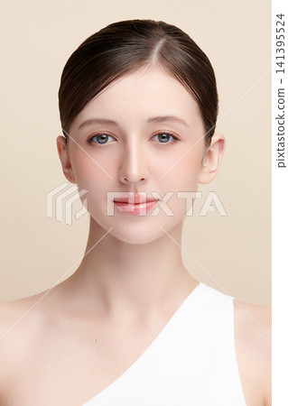 A beautiful young Asian woman with clean, fresh skin against a beige background. Skincare, facial treatment, cosmetology, beauty, and spa. An elegant portrait of an Asian woman. 141395524