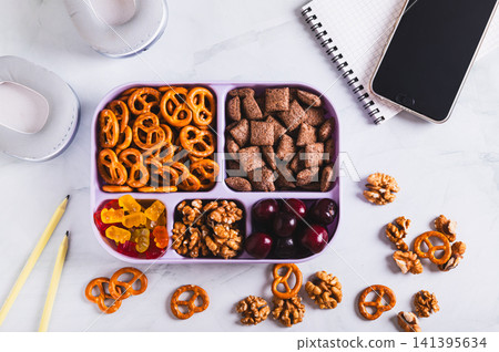 Snackle box filled with berries, pretzels, marmalade and nuts for snacking on the table top view Snackle box filled with berries, pretzels, marmalade and nuts for snacking on the table top view 141395634