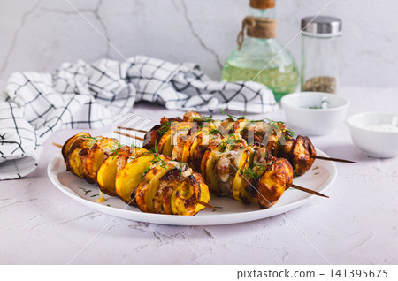 Meat and potatoes baked on skewers in an air fryer on a plate on the table 141395675