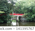 A red bridge over a pond in the forest 141395767