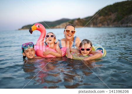 Family enjoying summer vacation swimming in ocean with inflatables Family enjoying summer vacation swimming in ocean with inflatables 141396206