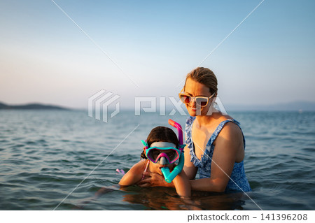 Mother and daughter enjoying snorkeling on a sunny day in the ocean Mother and daughter enjoying snorkeling on a sunny day in the ocean 141396208
