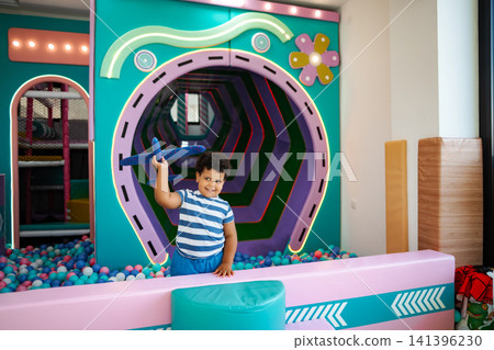 Young boy playing with toy airplane in colorful ball pit Young boy playing with toy airplane in colorful ball pit 141396230