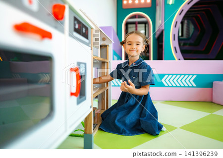 Little girl playing with toy kitchen in playroom Little girl playing with toy kitchen in playroom 141396239