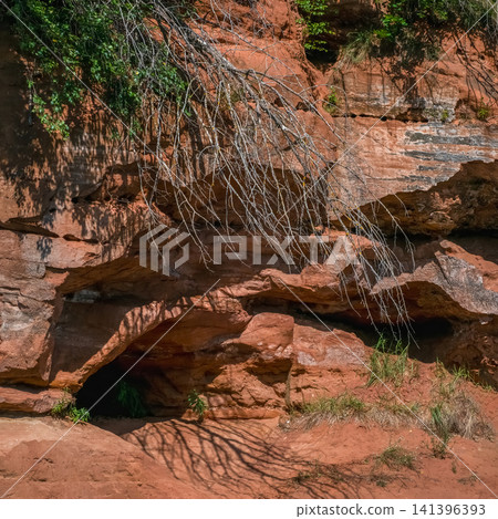 Entrance to a small cave in a red sandstone cliff on a sunny day. Entrance to a small cave in a red sandstone cliff on a sunny day. 141396393