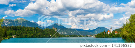 Panoramic view of Lake Bled in Slovenia featuring Bled Castle perched on a cliff and the iconic Church of the Assumption on Bled Island, surrounded by the Julian Alps. 141396582