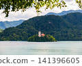 Scenic view of Lake Bled in Slovenia with turquoise water, the iconic Church of the Assumption on Bled Island, surrounded by forests and the majestic Julian Alps. 141396605