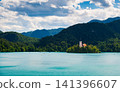 Scenic view of Lake Bled in Slovenia with turquoise water, the iconic Church of the Assumption on Bled Island, surrounded by forests and the majestic Julian Alps. 141396607