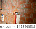 Plumber installing water supply pipes inside unfinished brick wall background 141396638
